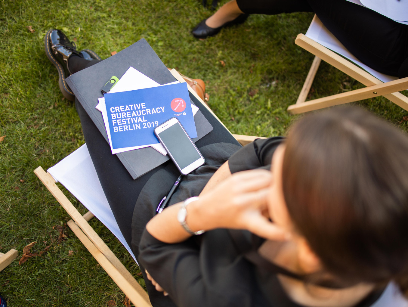 woman sitting outside with a festival 2019 card, papers and phone on her lap