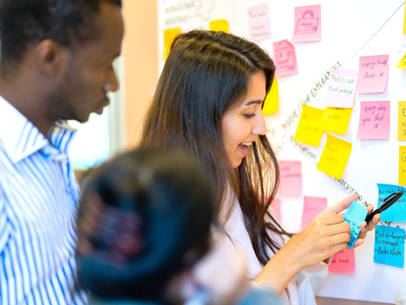 A group of people looking at a wall of Post-its.