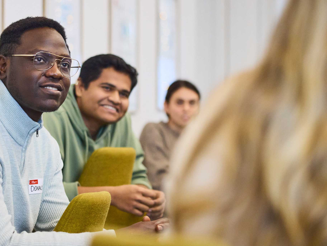 A person speaks while gesturing with hands during a group discussion in a workshop setting.