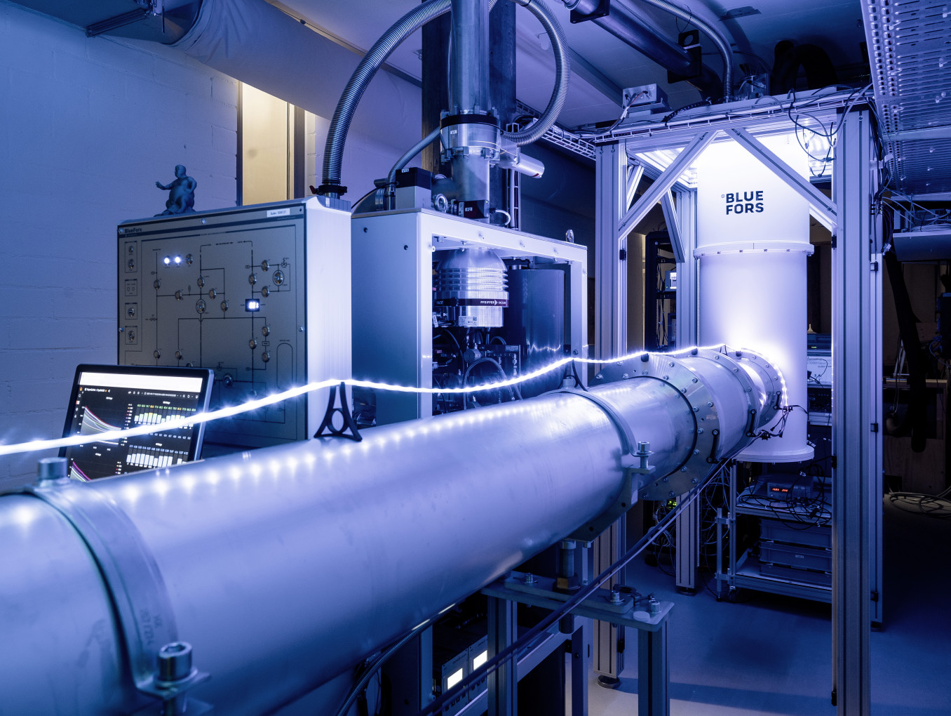 Section of a 30-meter-long cryogenic quantum link (front), allowing for the exchange of quantum information between two dilution refrigerators. One of them is depicted in the back of the photo. Each dilution refrigerator operates a quantum device at millikelvin temperatures