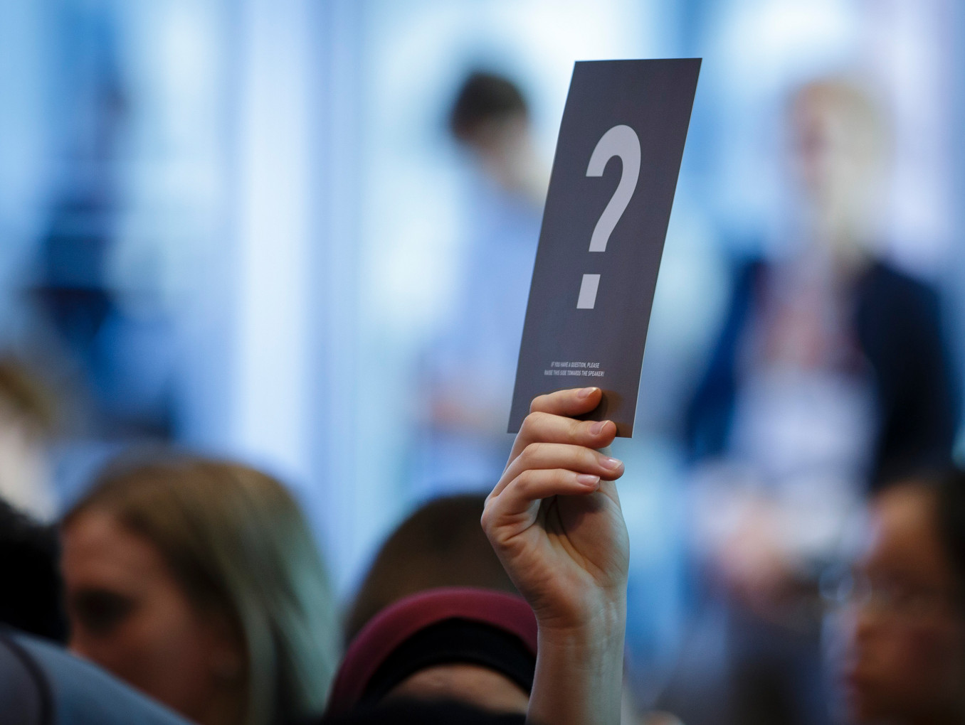 Someone in the Audience holds up a question mark to ask a question.