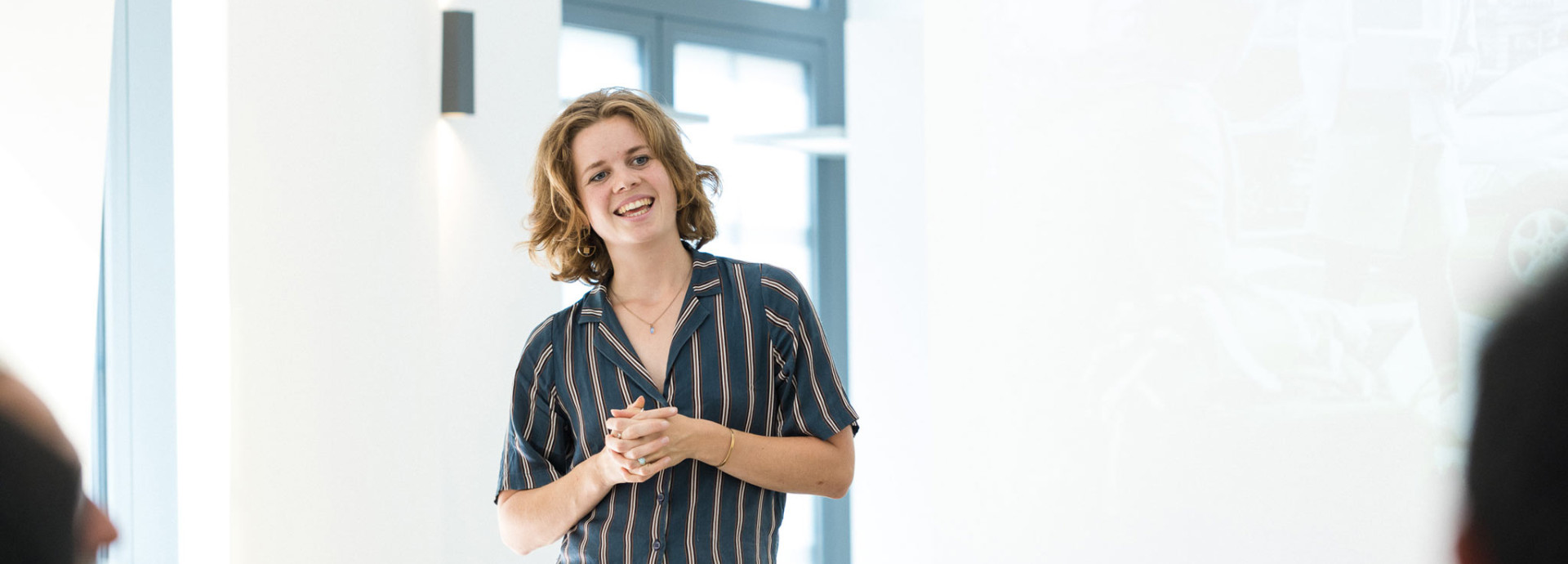 A person is excitedly standing in front of a group smiling.