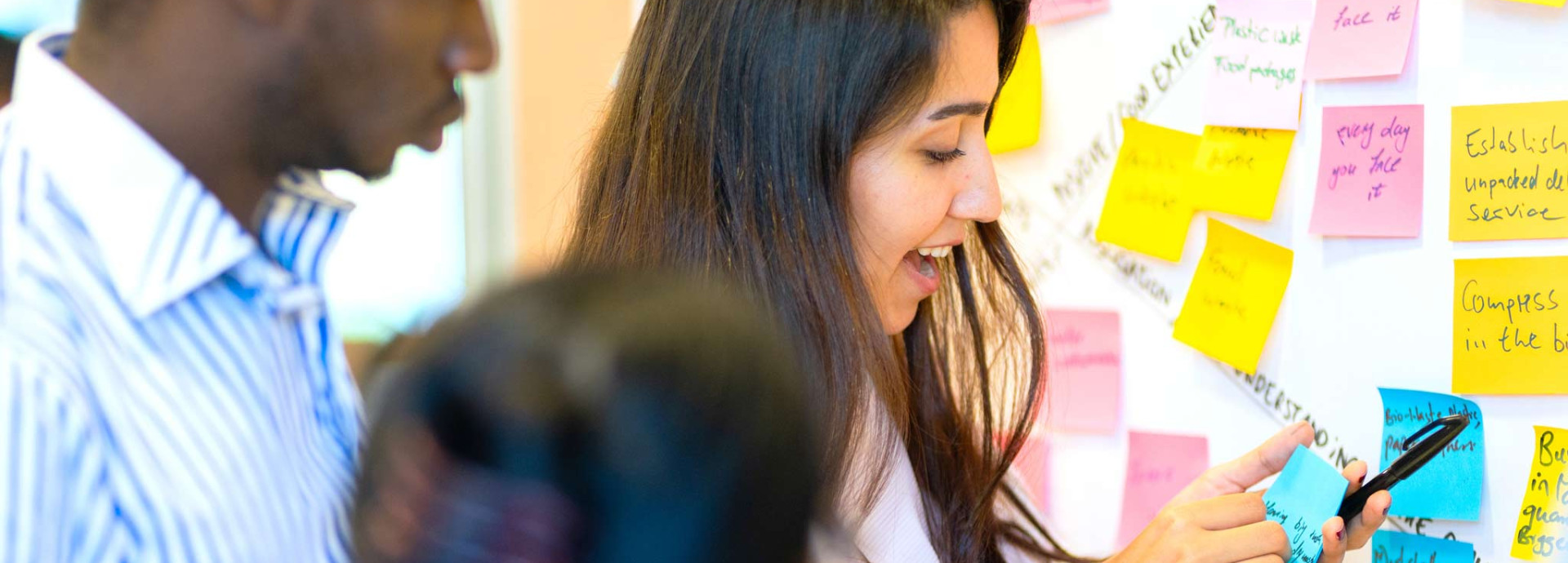 A group of people looking at a wall of Post-its.