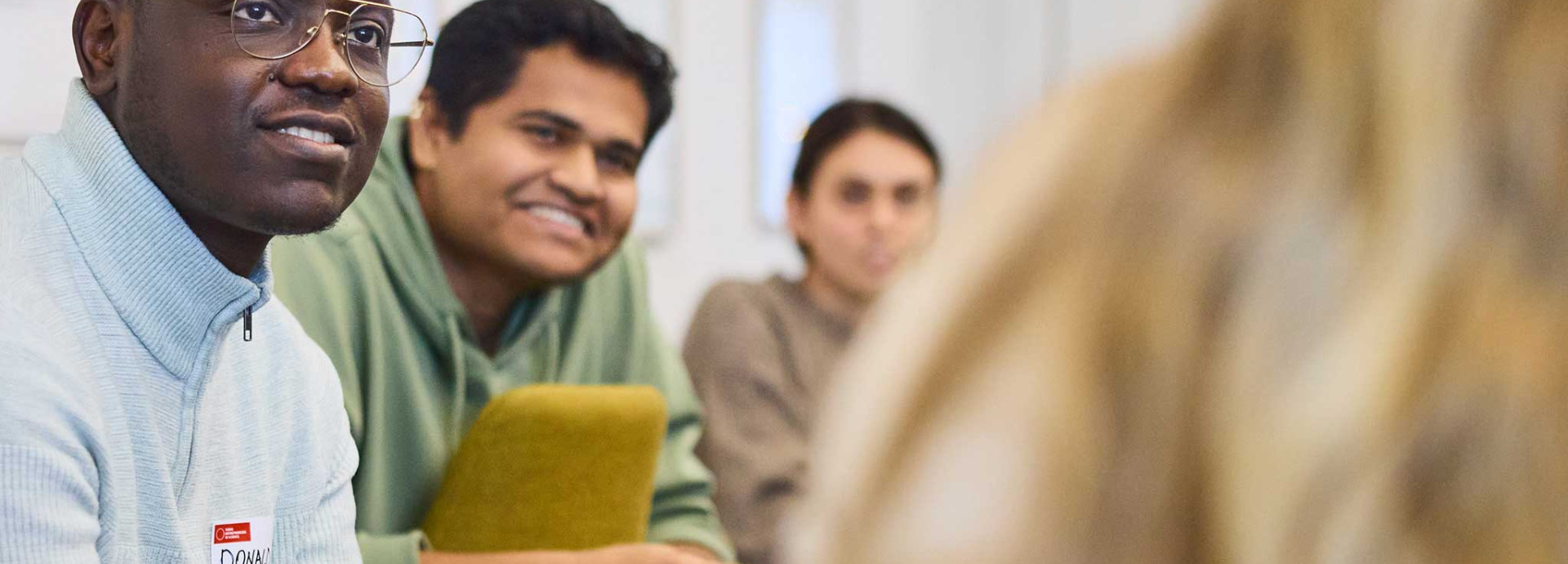 A person speaks while gesturing with hands during a group discussion in a workshop setting.