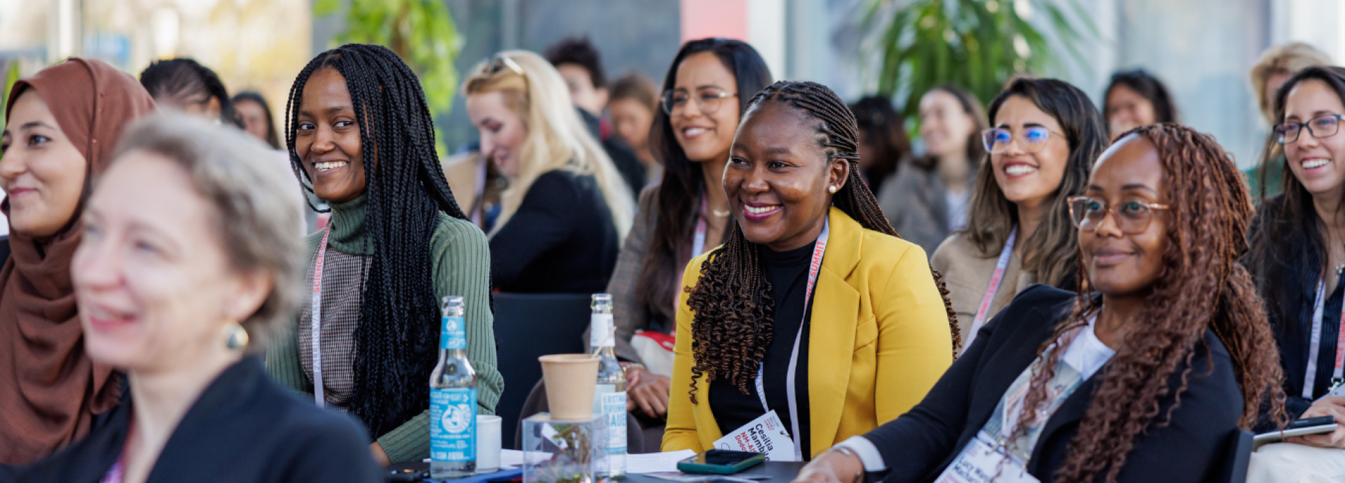 A group of women are sitting in the audience, smiling, looking at the speaker out of frame.