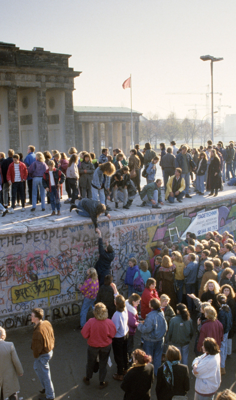 Fall of the Berlin Wall: people from East and West Berlin climbing on the Wall at the Brandenburg Gate, Berlin, Germany