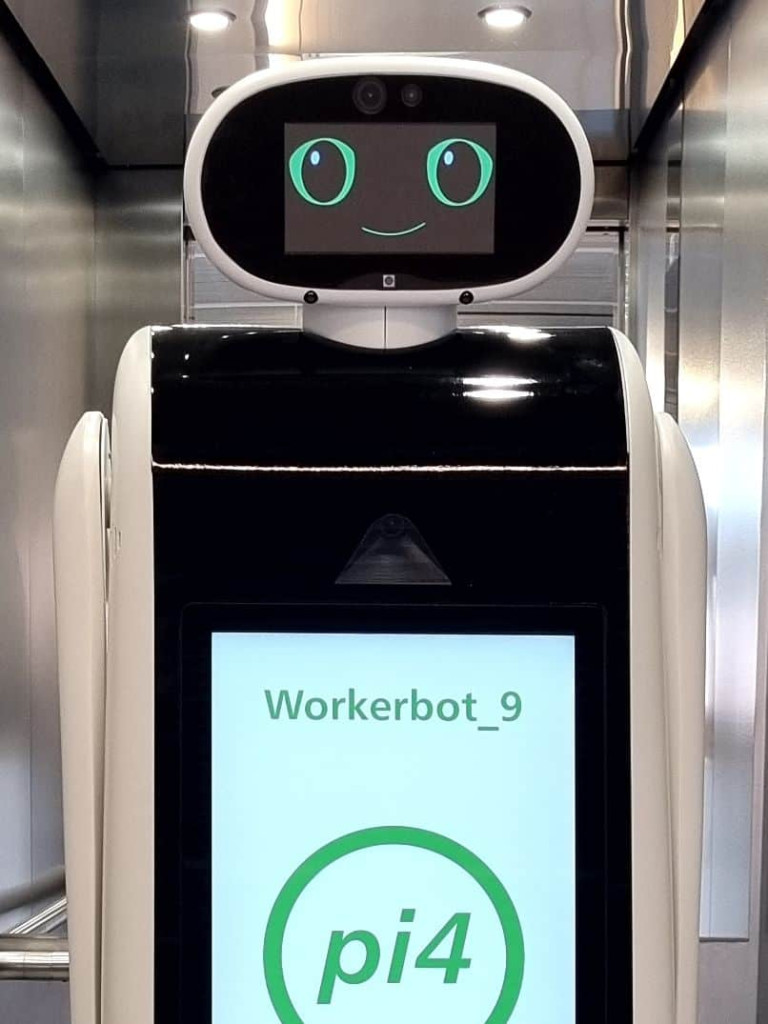 Photo of ROBOT ROMI, it is smiling and has a screen for a face