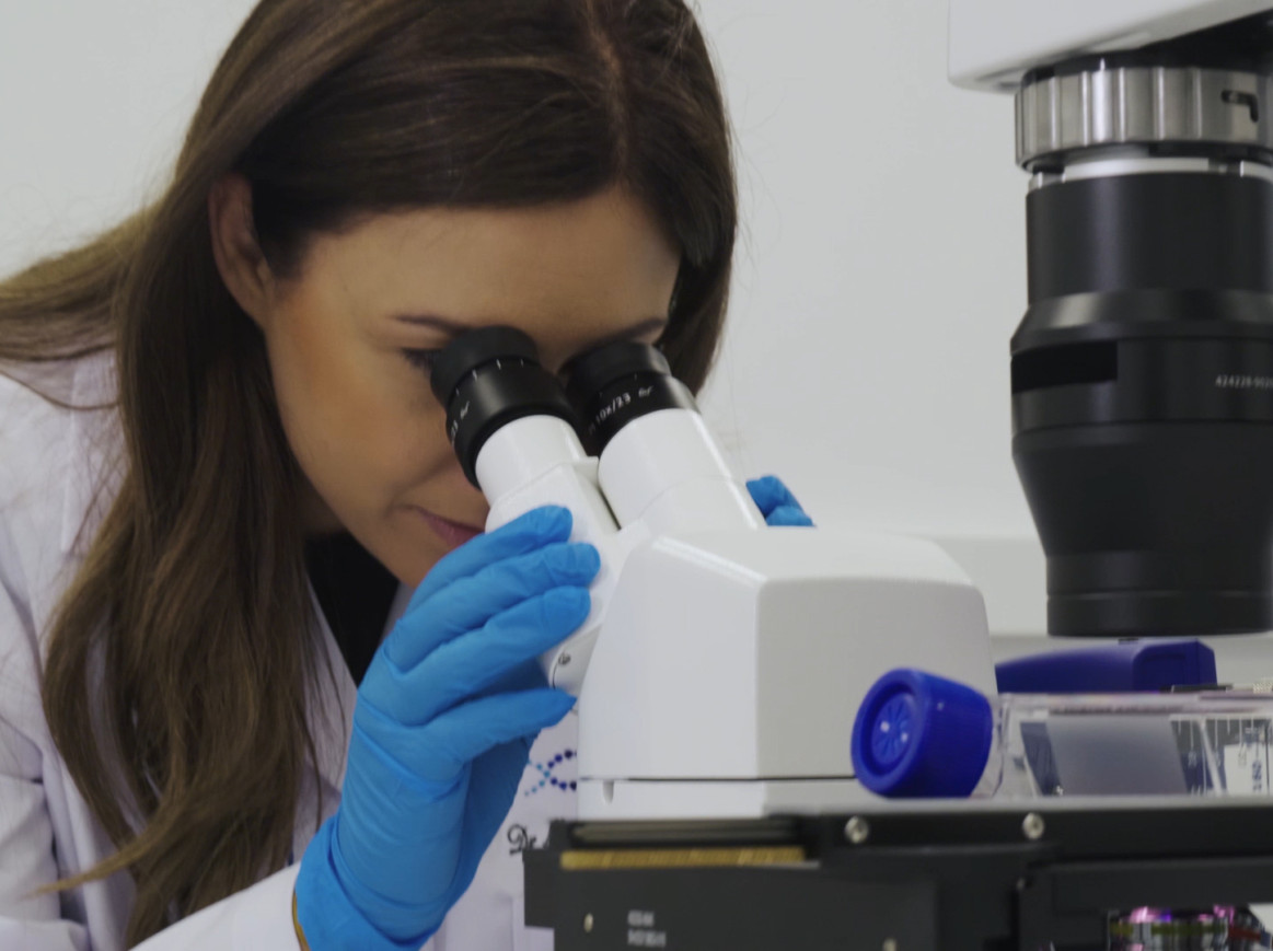 Faculty looking through microscope. 