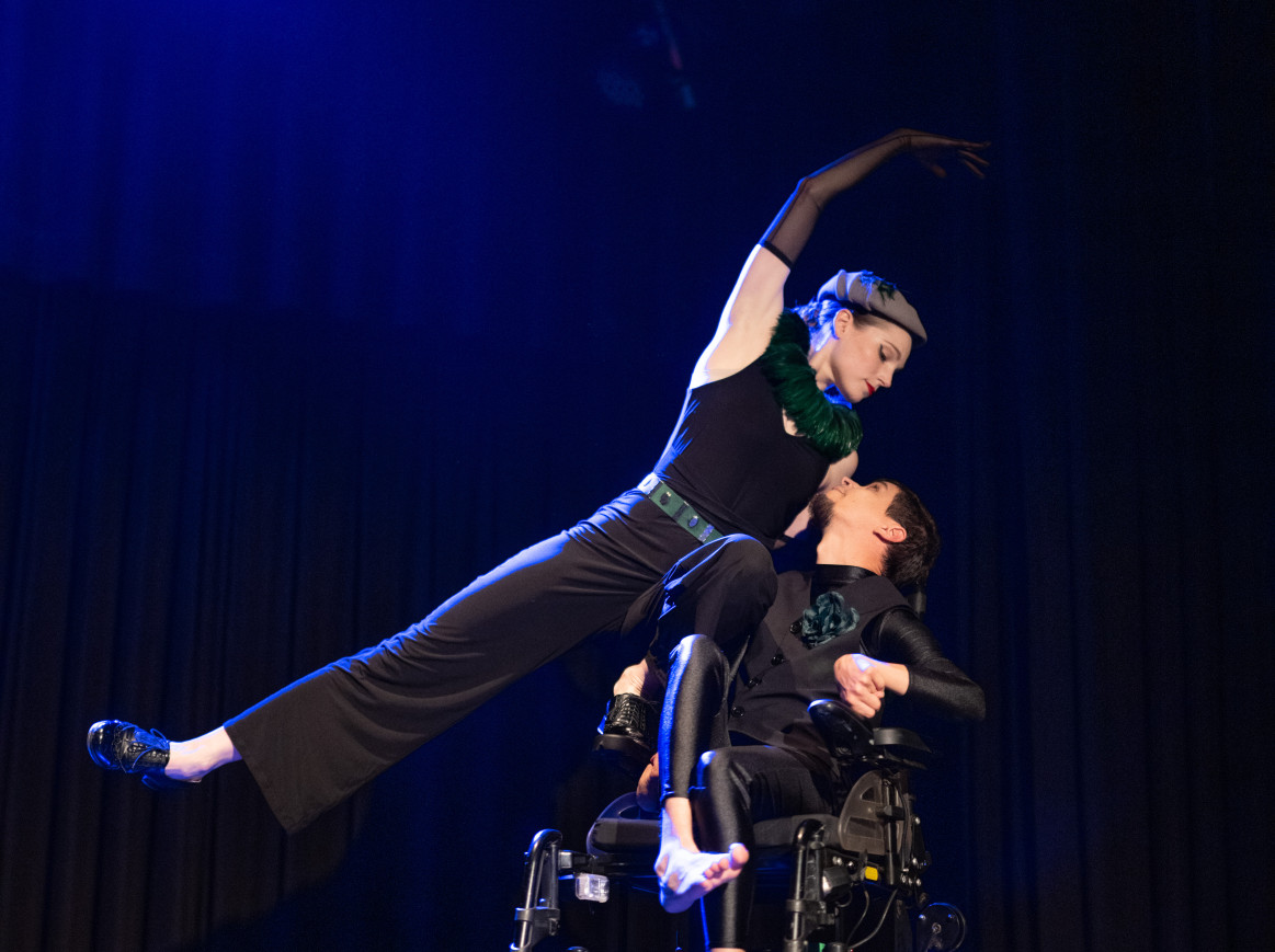 The photo show a dance position  between a dancer in E-wheelchair (Karoly Toth) and a dancer without handicap (Anna S. Harms) in the performance "Human Design"