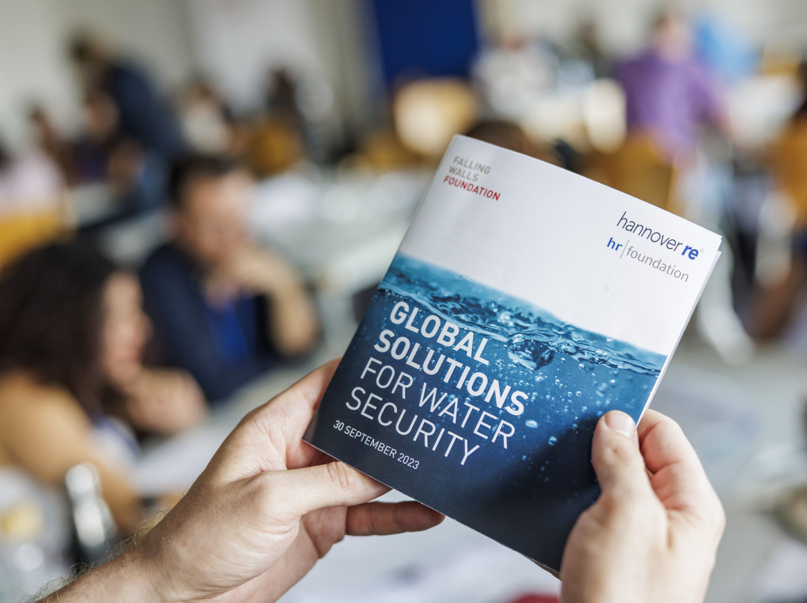 Someone holding the printed programme of the Falling Walls Summer School 2023: Global Solutions for Water Security