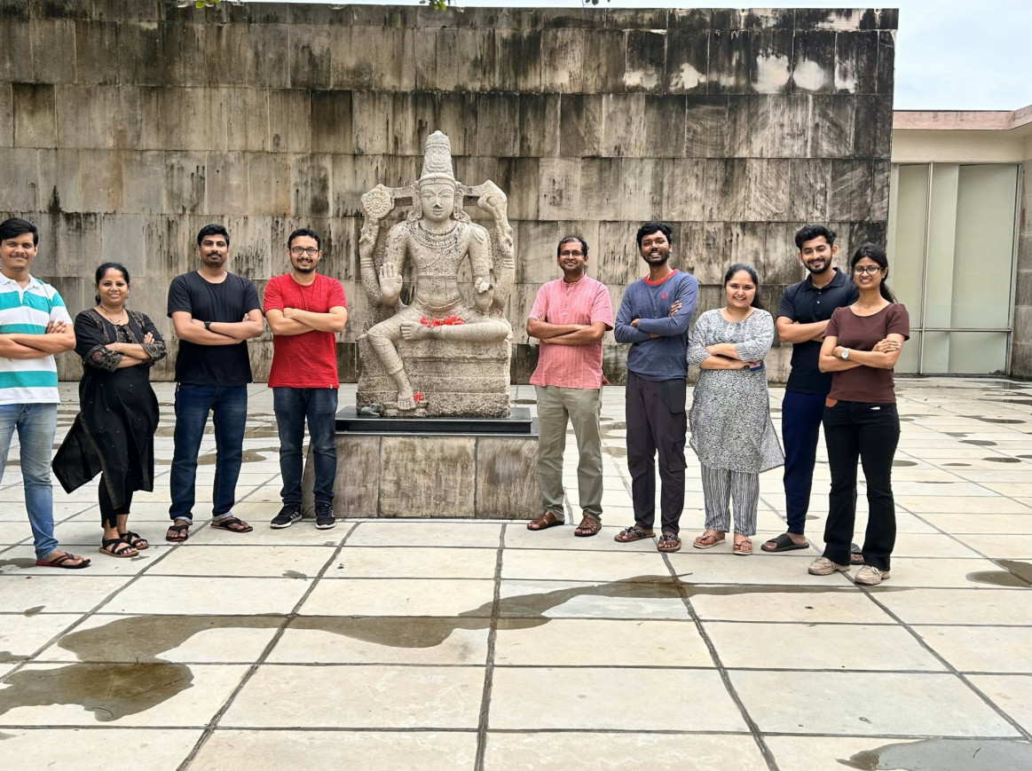 Group shot with Vivek Polshettiwar and his team next to a statue
