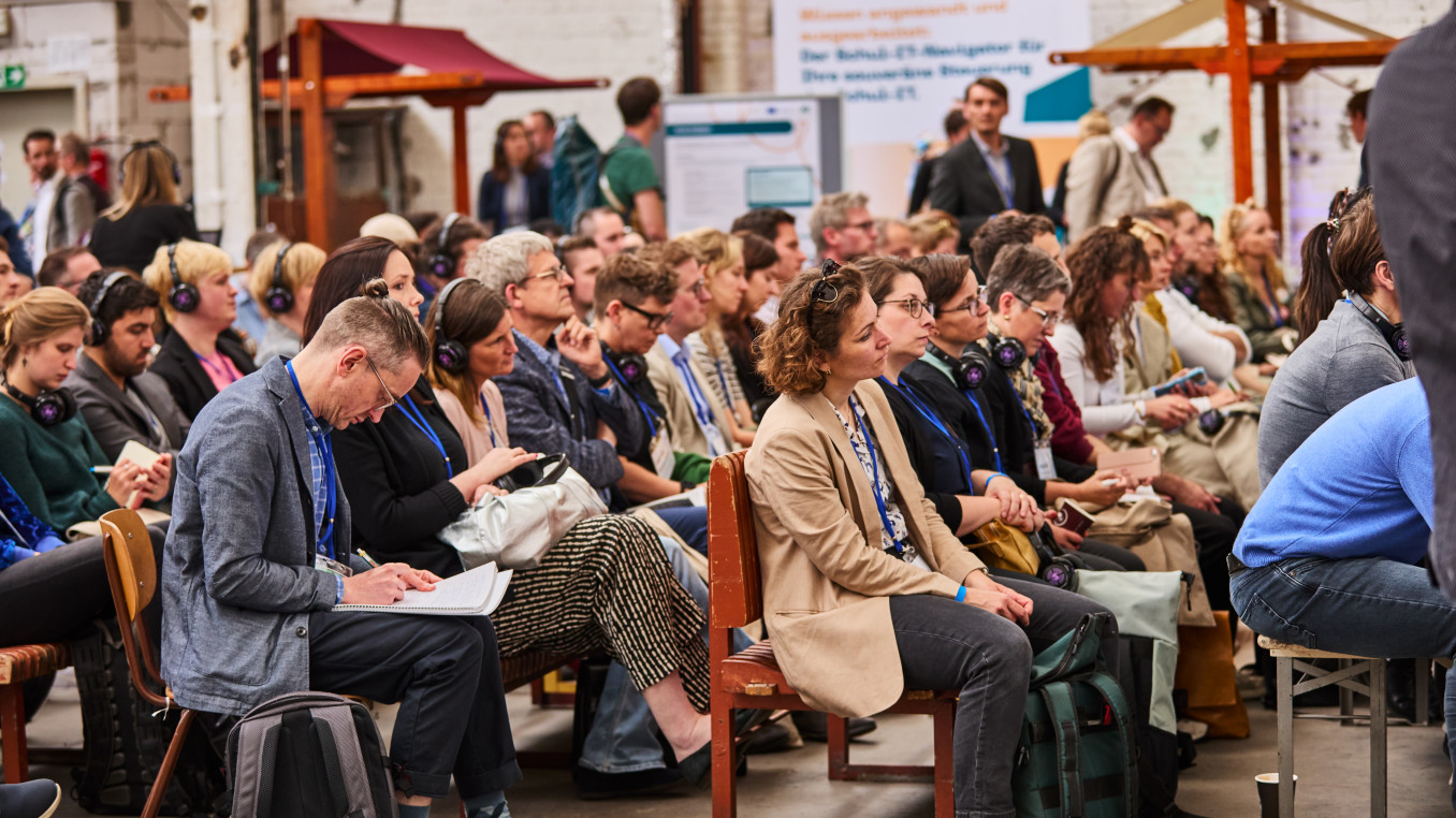 audience sitting in front of the stage, listening and writing 