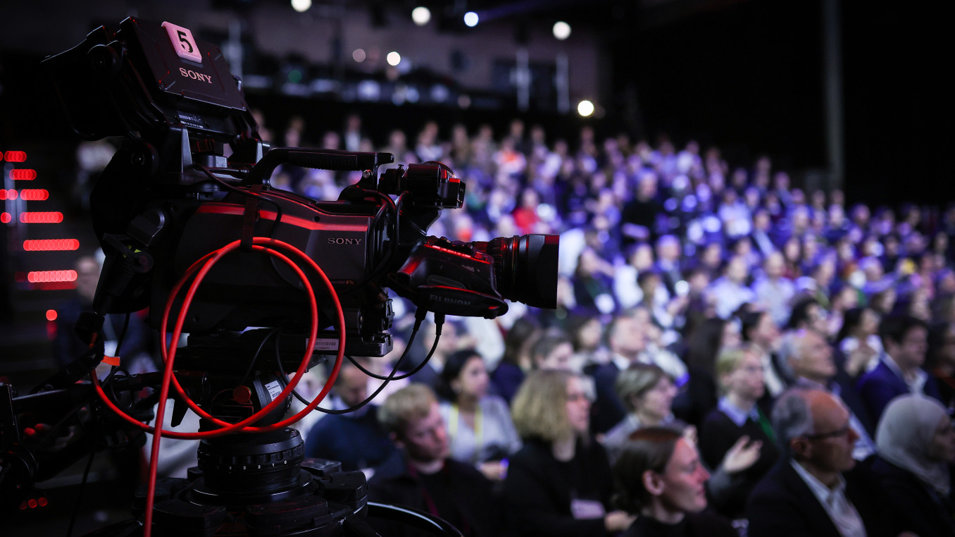 Camera recording a presentation at Falling Walls Science Summit 2023, with the audience in the background