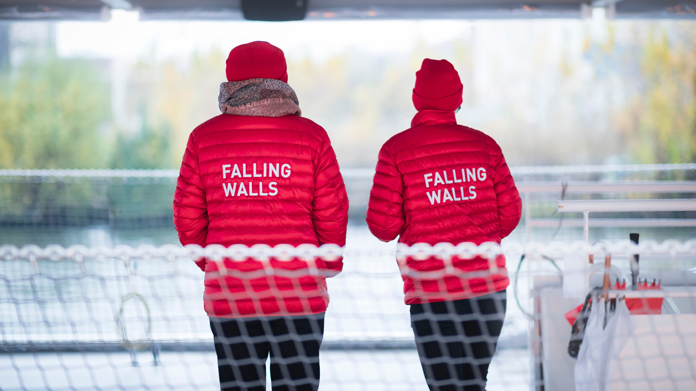 Two people in red jackets with Falling Walls written on the back.